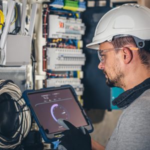 Man, an electrical technician working in a switchboard with fuses. Installation and connection of electrical equipment.